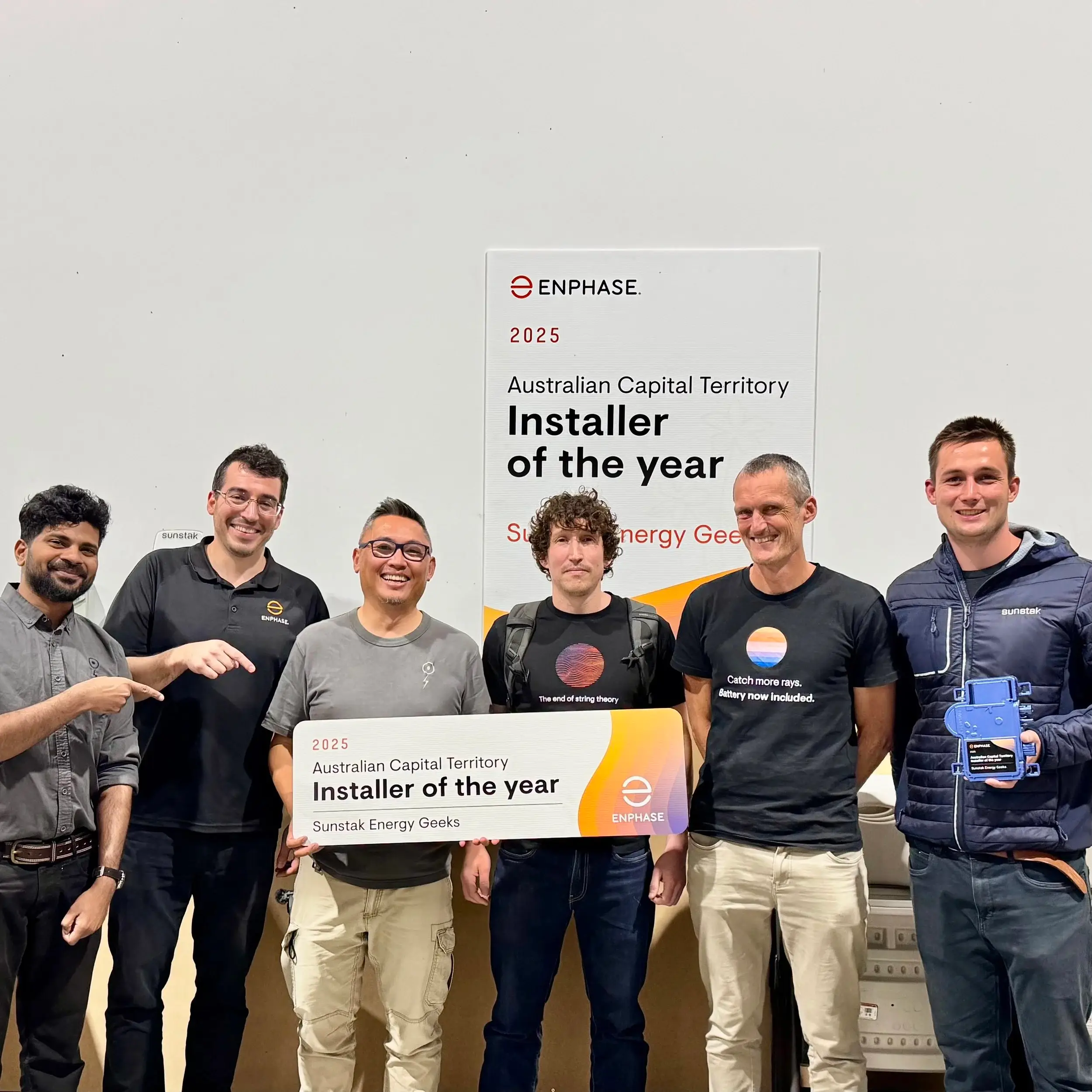 Six people in front of an Enphase sign reading 2025 Australian Capital Territory Installer of the year, holding a board with the same words and Sunstak Energy Geeks on it