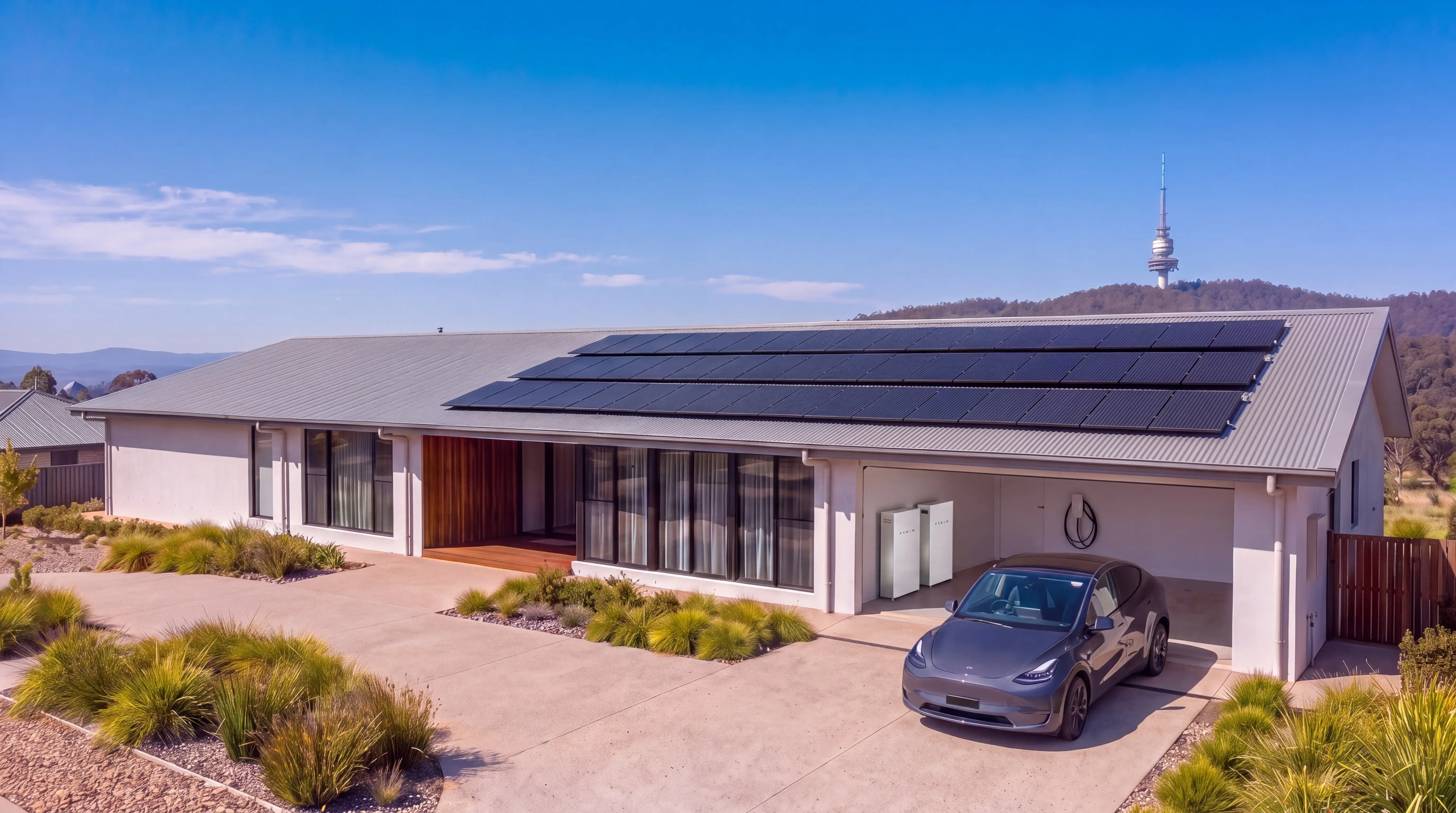 A visualisation of a long single-storey house of pale render and timber battens, black solar panels on its mid-grey steel roof under a deep blue sky, the garage open with two white home batteries and a car charger inside, a dark grey car on the concrete driveway, and a wooded ridge behind