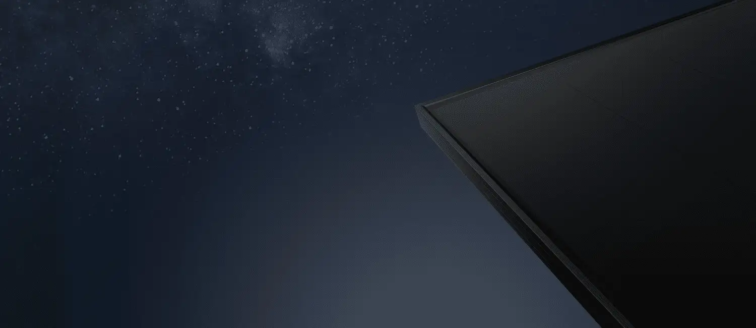 The corner of a black solar panel seen from below against a night sky full of stars